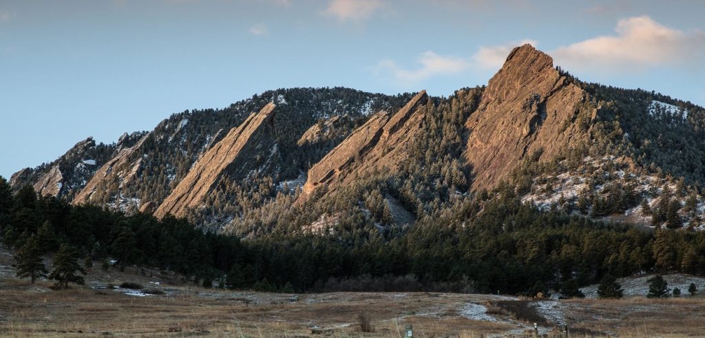 A family travels to Chautaqua Park in Boulder with mountains in the middle of a field with trees in the background. Perfect for outdoor adventures for kids near Denver.