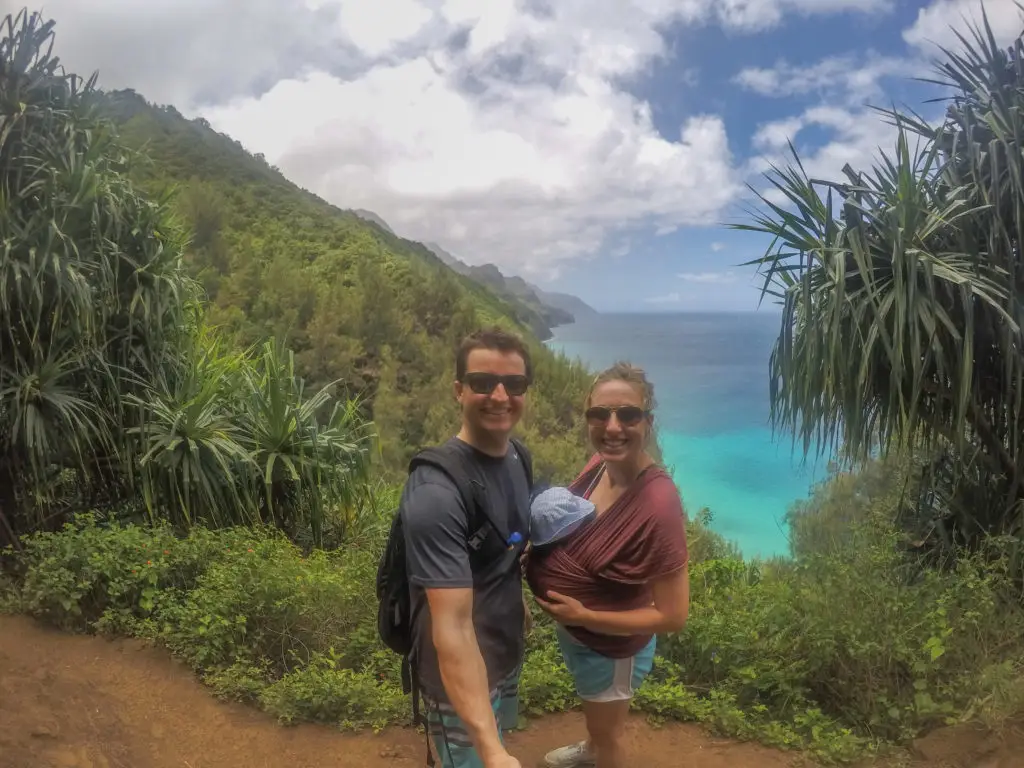 A couple enjoying an adventurous hike along the ocean in Hawaii.  Something you can do while traveling with your baby.  