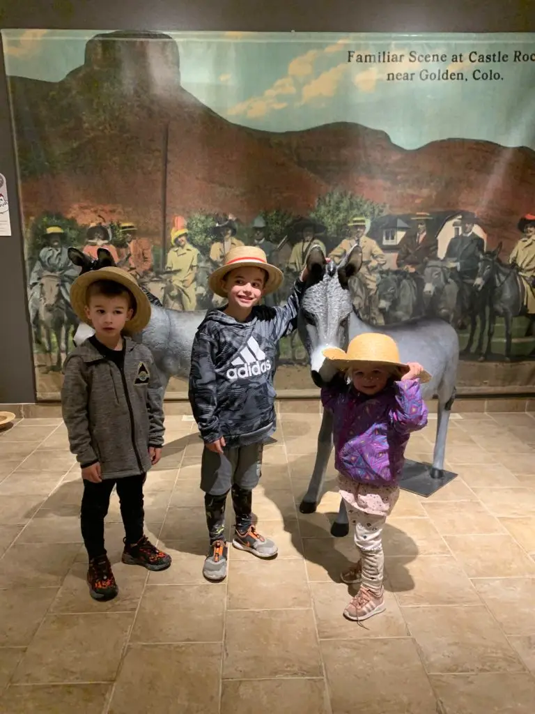 Three kids posing in front of a statue at Golden History Museum.  One of our favorite things to do in Golden with kids.