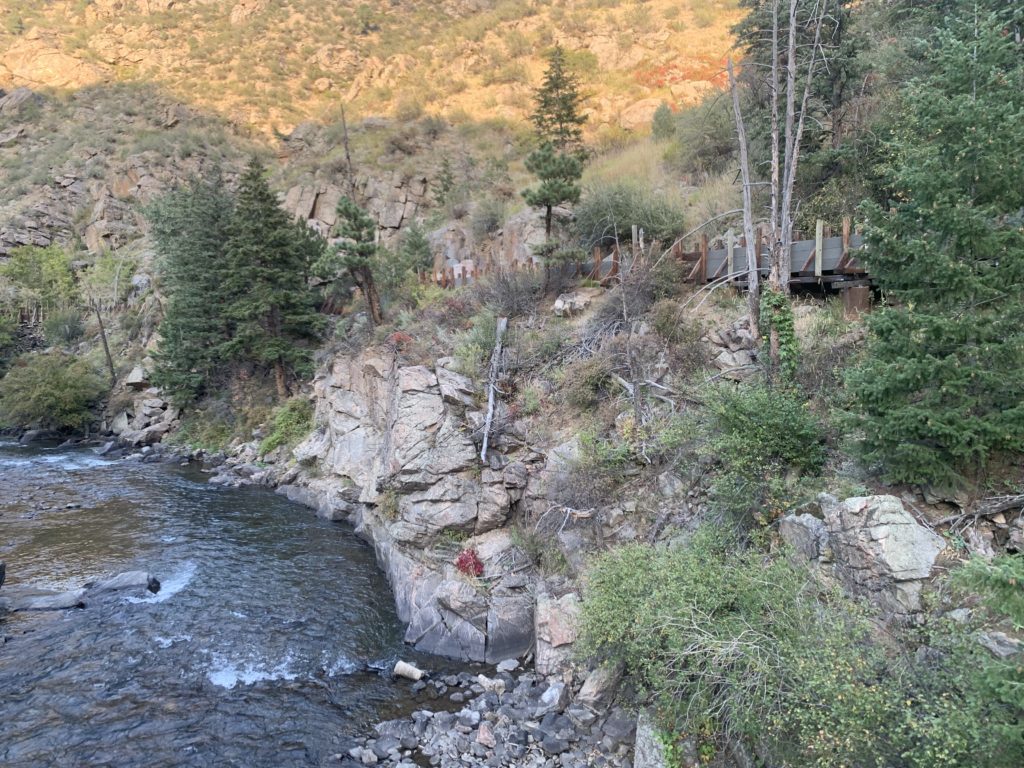 A rocky river with a bridge and trees in the background.  A hike for kids in Golden.