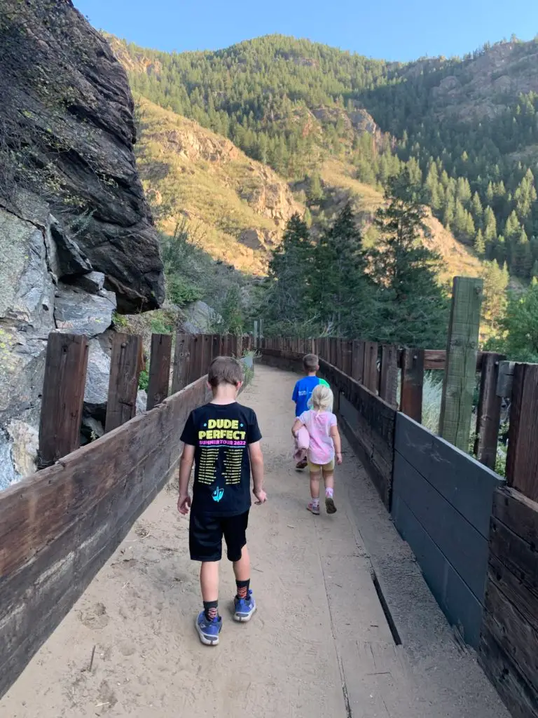 Three children walking on a wooden bridge in the mountains on a hike for kids in Golden.