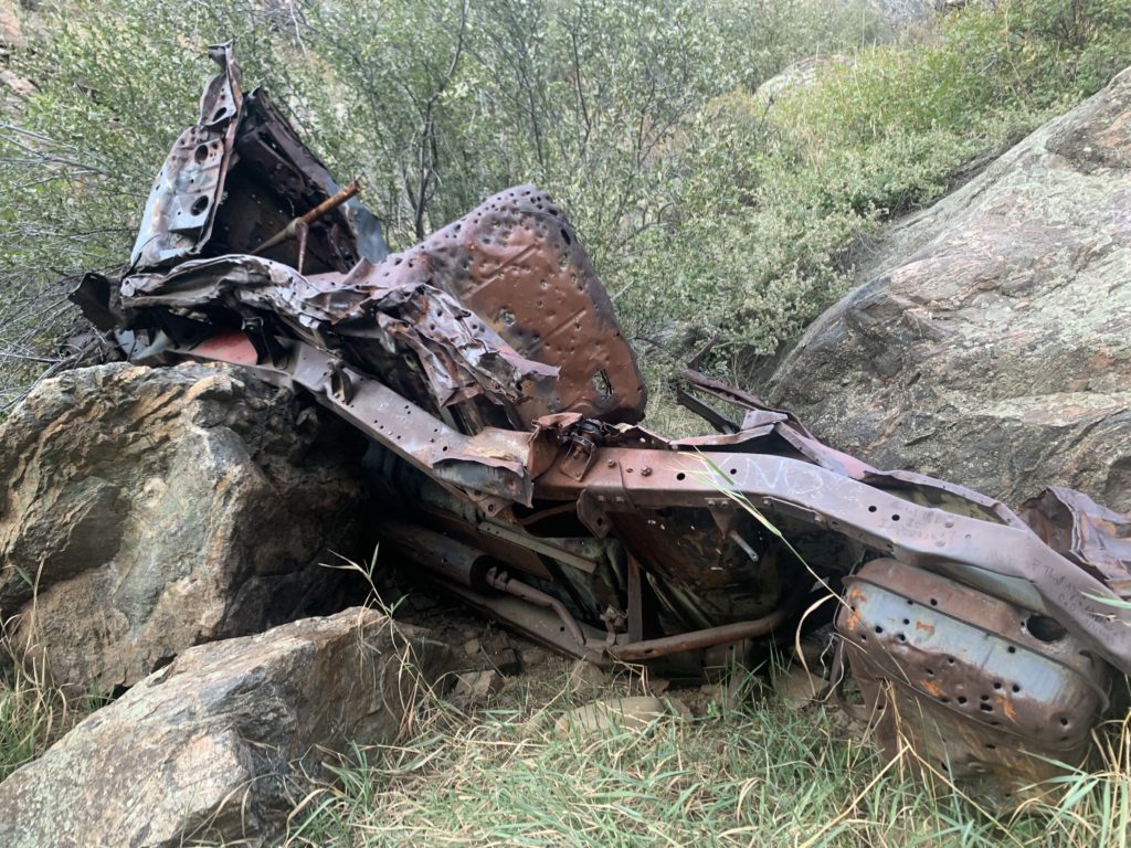 A rusted car lying on top of a rock.