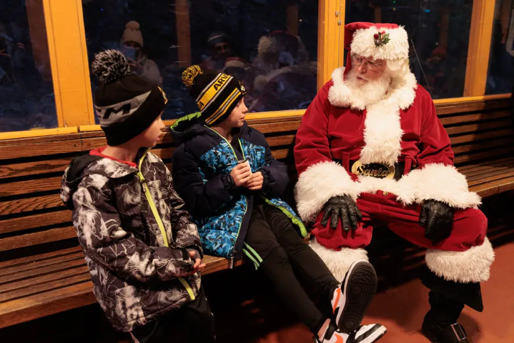 Santa's Lighted Forest with kids.  Santa claus sitting on a bench.