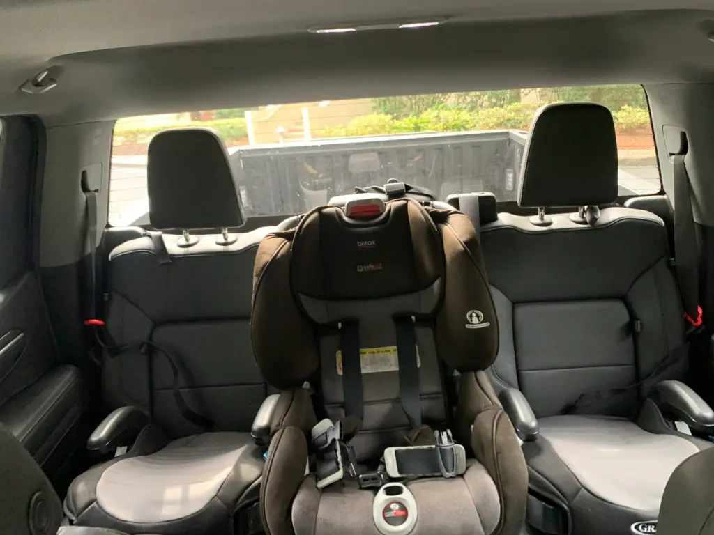 A pickup truck with a baby car seat in the back seat.