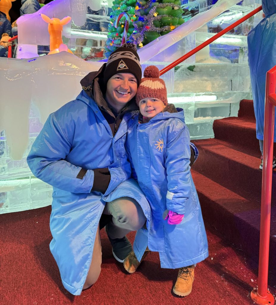 A man and a child posing in front of an ice castle.