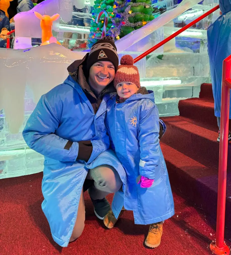 A man and a child posing in front of an ice castle.