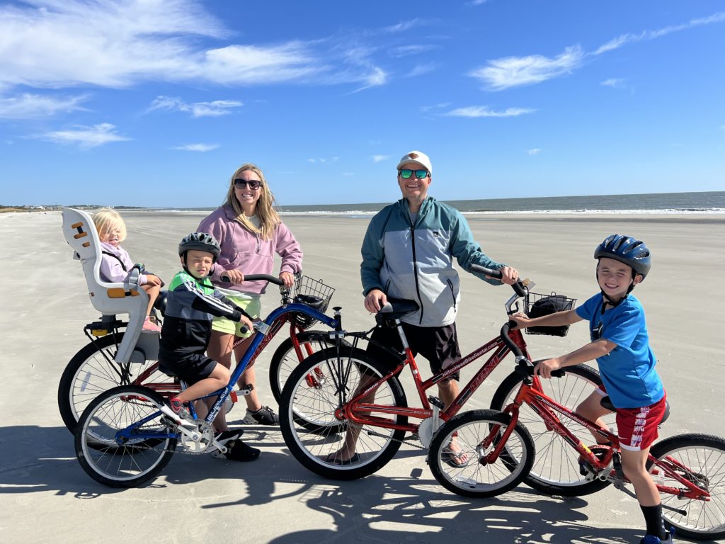 A family is posing with their bicycles on the beach on their Hilton Head family vacation.