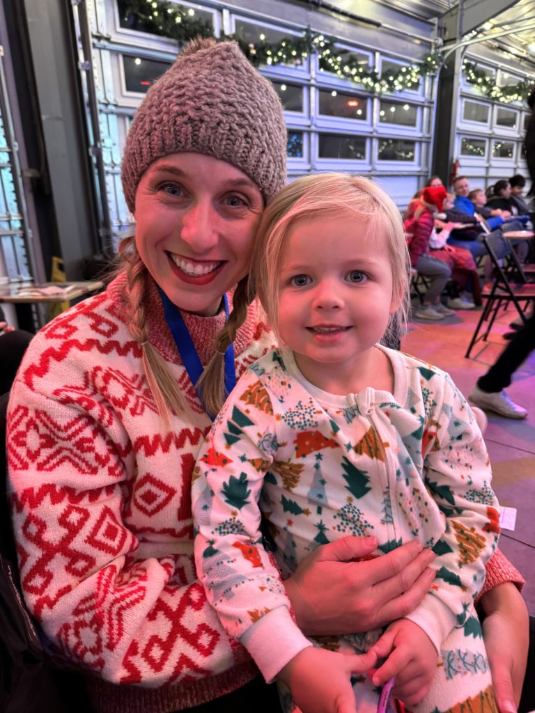 A woman holding a child at a christmas event called the Polar Express train ride