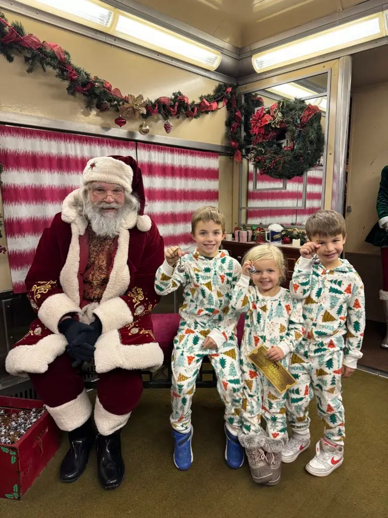 Santa claus on the Polar Express train ride train with children in pajamas.