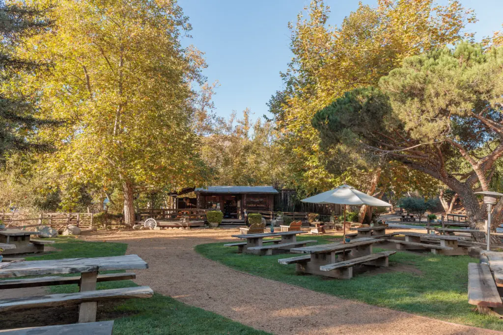 Wooden picnic tables in a grassy area. Family glamping in Santa Barbara.