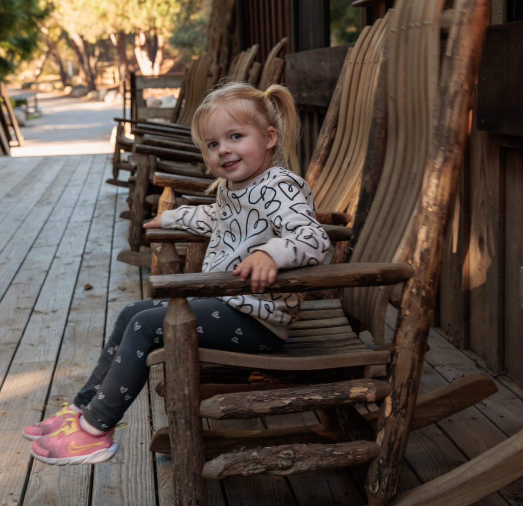 A little girl sitting on a wooden rocking chair. Family glamping in Santa Barbara.