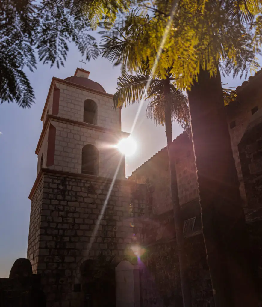 A stone building with a clock tower.  Old Mission Santa Barbara with kids.