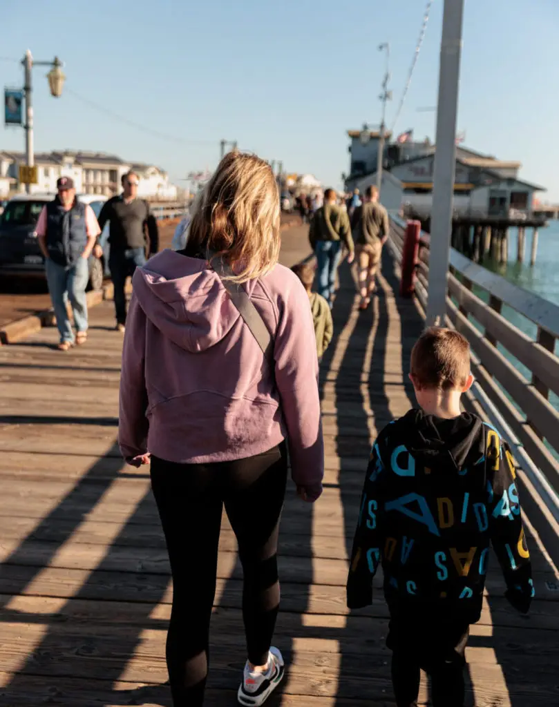 A woman and a child walking on a wooden pier. Stearns Wharf with kids.