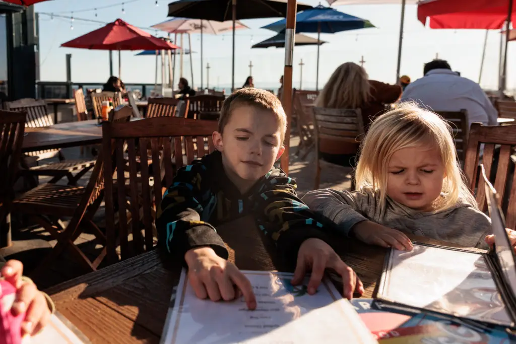 Two children sitting at a table at an outdoor restaurant. Stearns Wharf with kids.