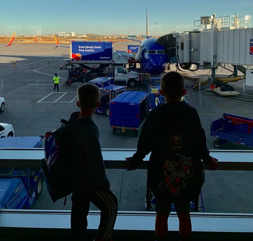 Two boys looking out of a window at an airport.  Is Clear worth it for families.  We think so.