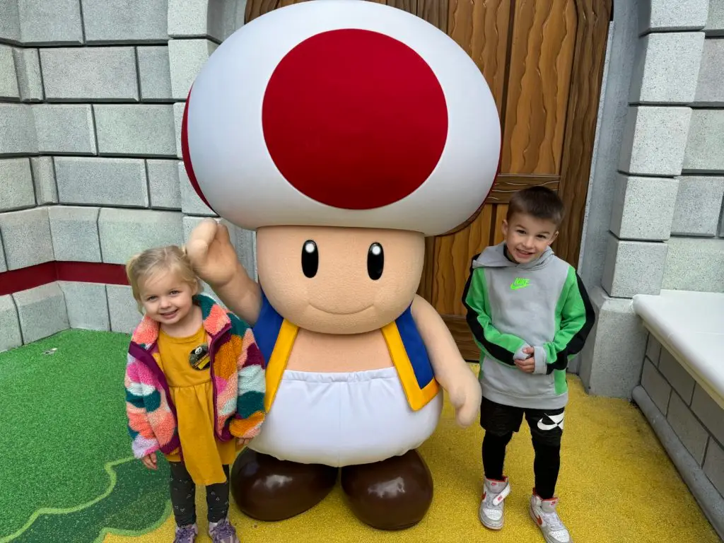 Two children standing next to a giant toad for our Super Nintendo World review