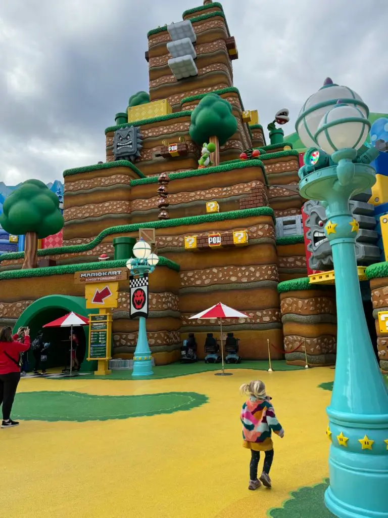 A child is standing in front of a building in a theme park for our Super Nintendo World review