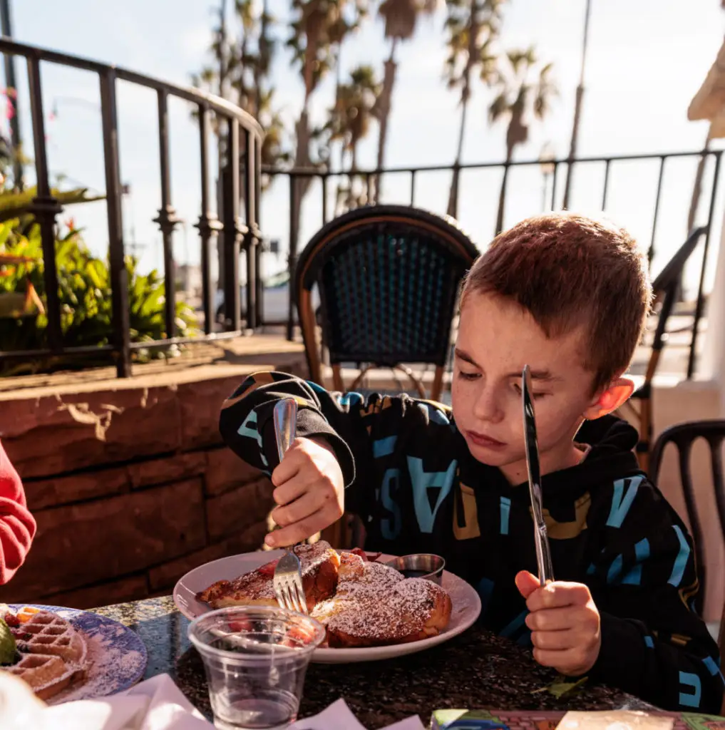 A boy is eating a plate of food. Breakfast in Santa Barbara with kids.