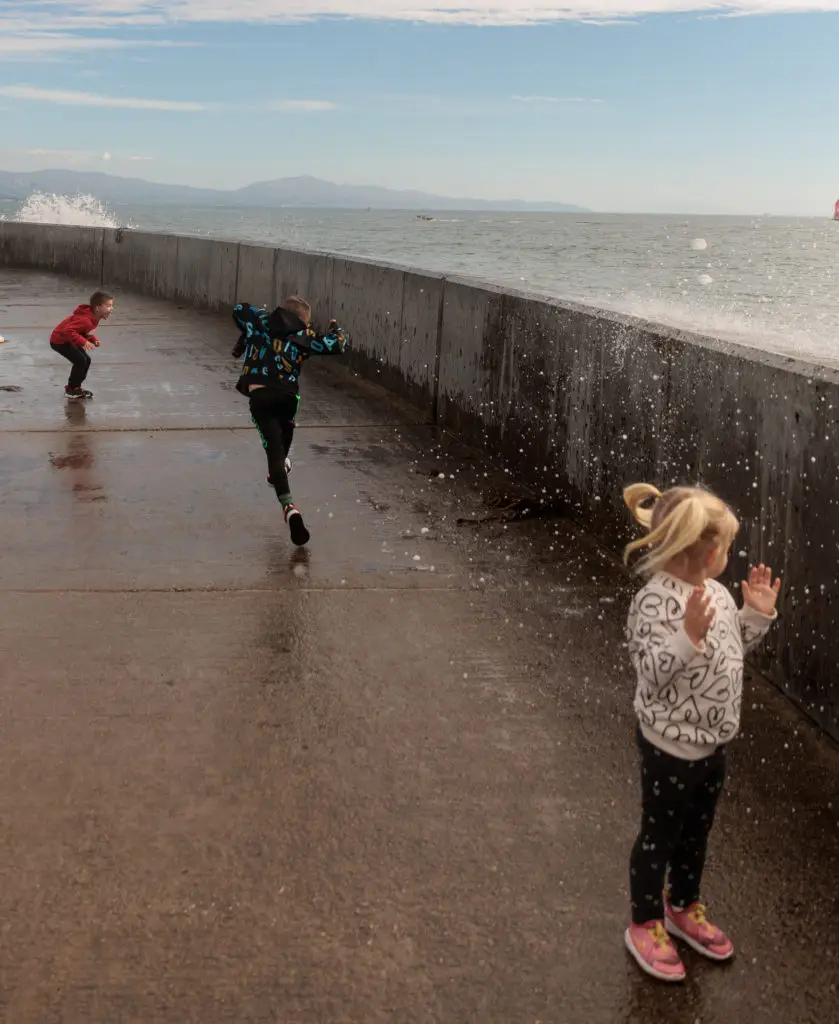 A group of children playing at the Santa Barbara Harbor Breakwater Wall. 