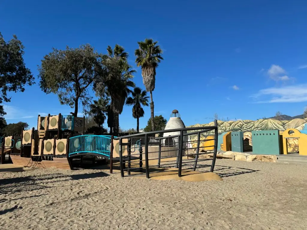 A children's playground in the sand with palm trees. Santa Barbara Playgrounds