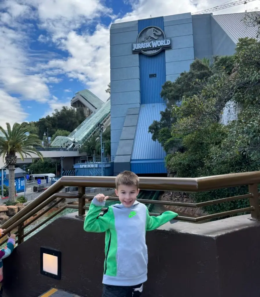 A young boy standing in front of a building at jurassic park.  Universal Studios Hollywood with Kids