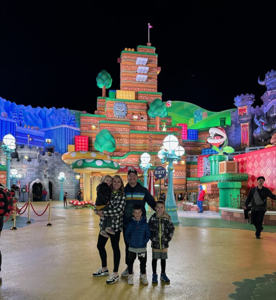 A group of people standing in front of Ninteno World at night. Universal Studios Hollywood with Kids