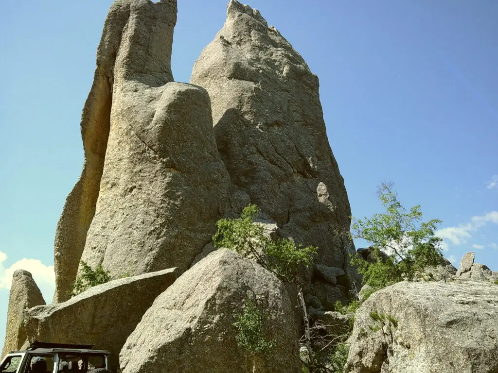 Large rock formations with green foliage at the base under a clear blue sky.  Camp Snap Discount Code.