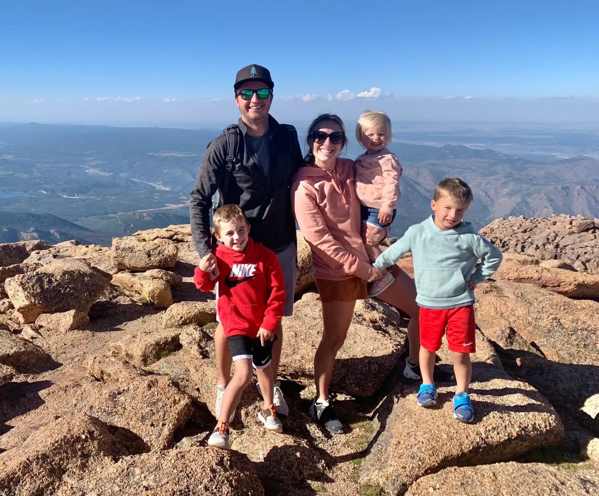 A family of kids posing on top of a mountain while traveling.