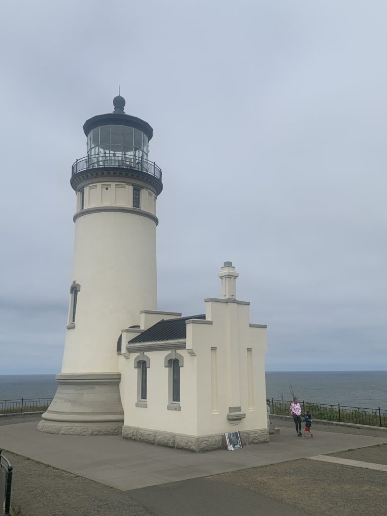 A lighthouse overlooks the ocean, offering an adventurous travel experience for kids.