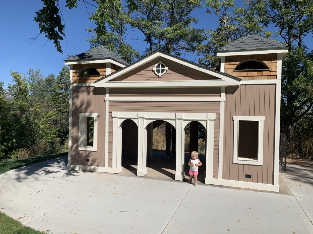 A little girl standing in front of a playhouse, sparking her sense of adventure.