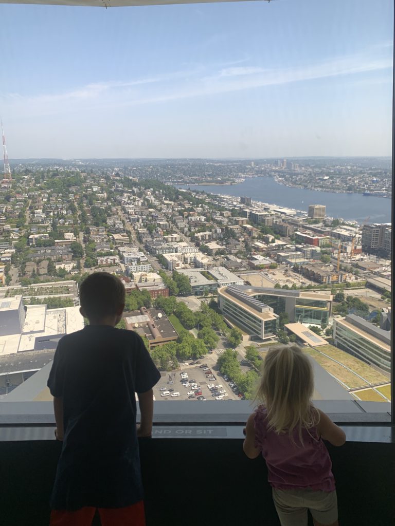 Two kids embarking on a Pacific Northwest Road Trip while gazing out a city window.