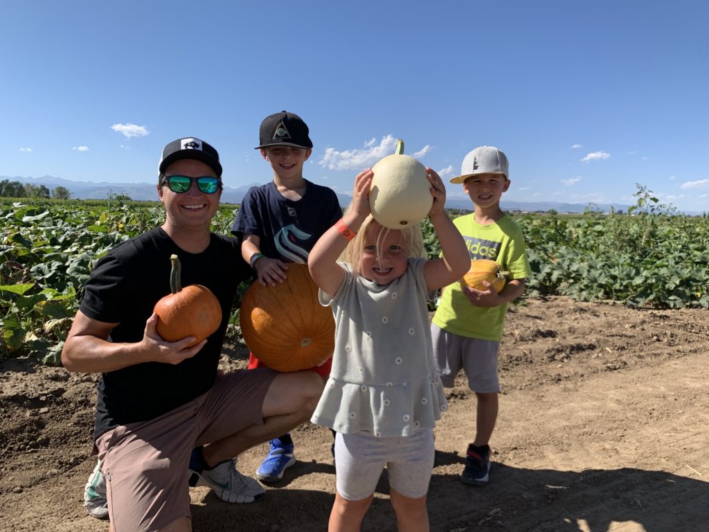 A group of people holding pumpkins in a field.