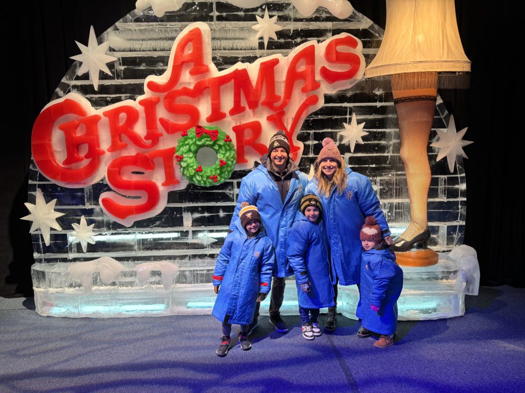 A family posing in front of a christmas story ice sculpture.