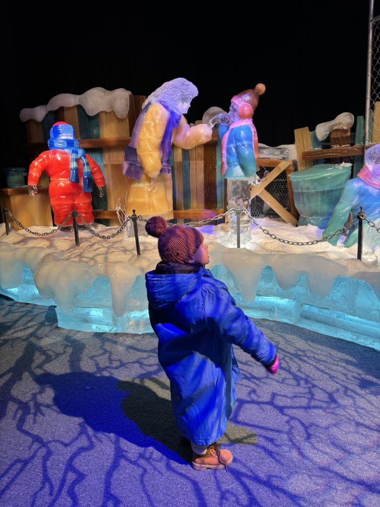 A child is standing in front of a display of ice sculptures.