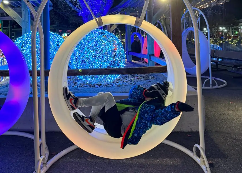 A person is laying in a swing chair in a park.