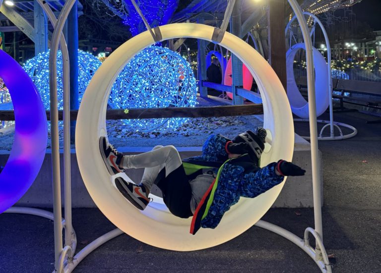 A person is laying in a swing chair in a park.