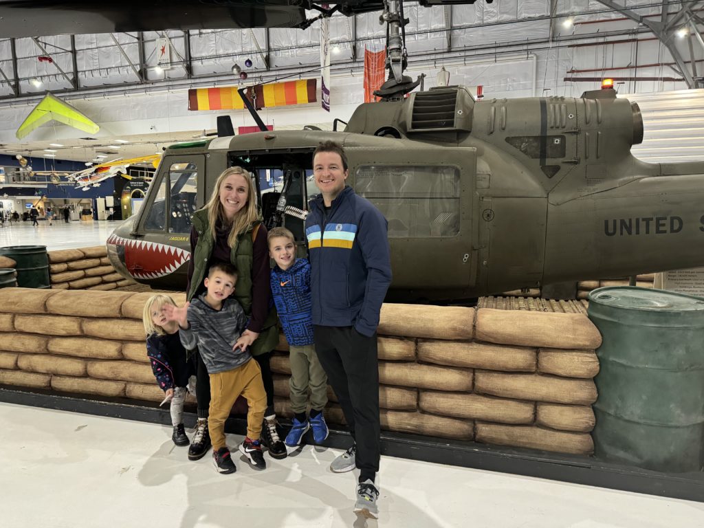 A family posing in front of a military helicopter.