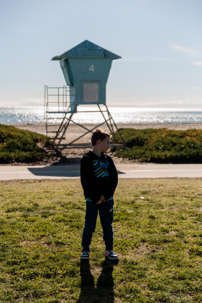 A boy is standing in front of a lifeguard tower. Beaches in Santa Barbara With Kids