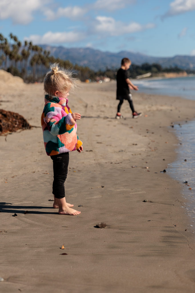 A little girl is standing on a beach playing with a frisbee. Beaches in Santa Barbara With Kids