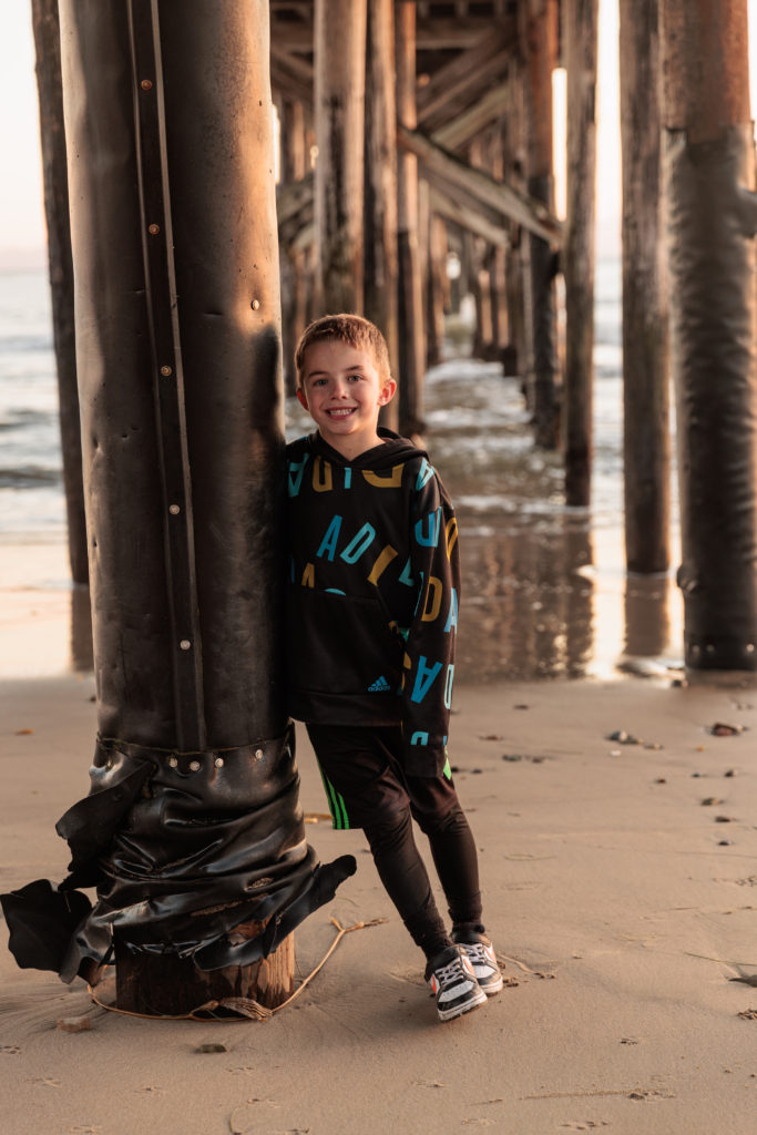 A young boy leaning against a pier. Beaches in Santa Barbara With Kids