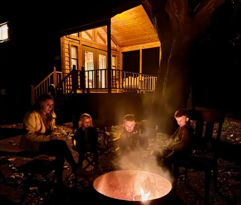 family around campfire at night in front of cedar cabin at el capitan resort in Santa Barbara California