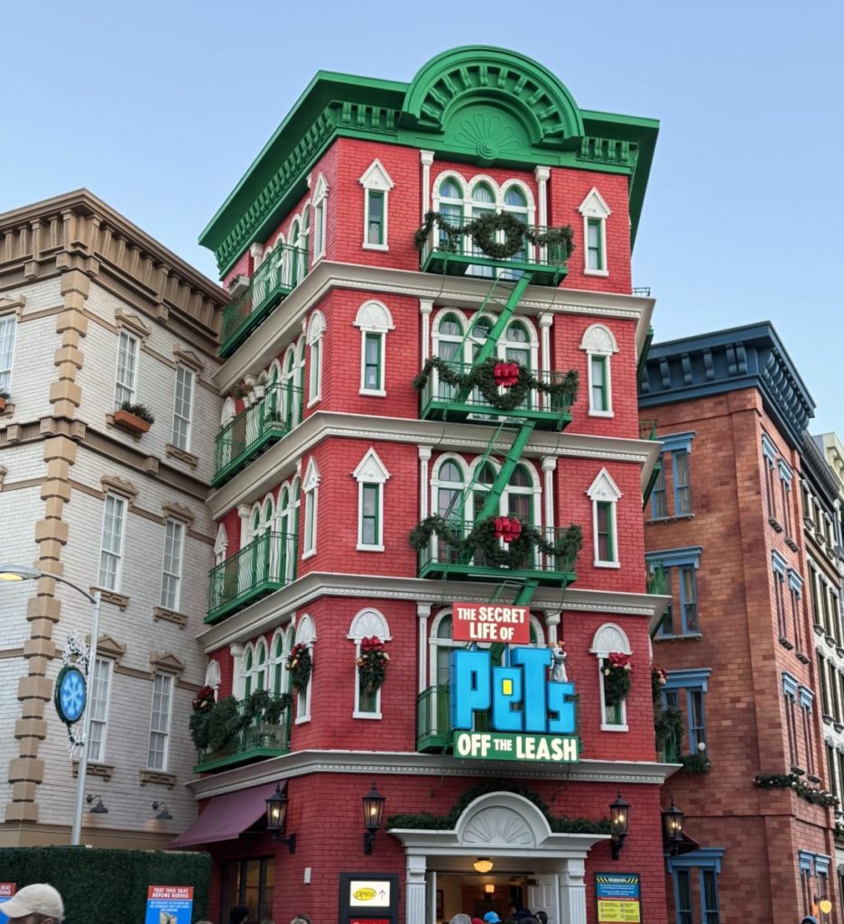 A red and green building with people walking in front of it. Universal Studios Hollywood with Kids