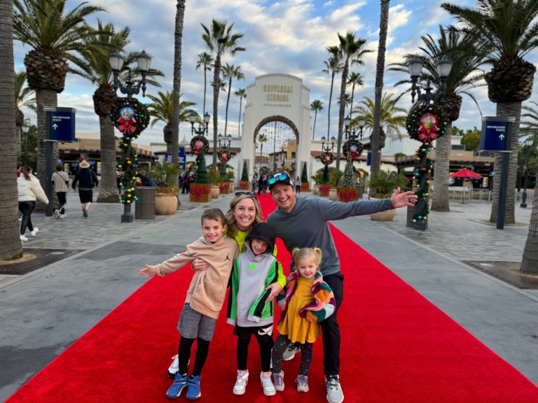 A family posing on a red carpet in front of palm trees.